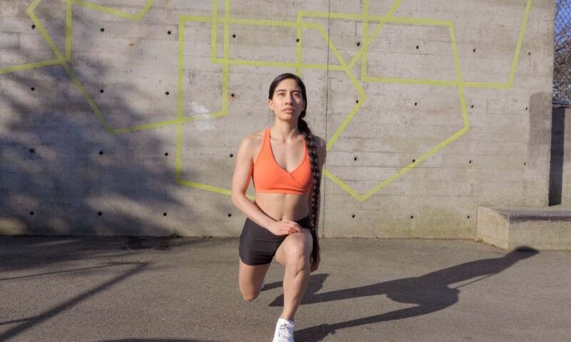 devojka u narandžastom topu i crnom šortsu trenira napolju